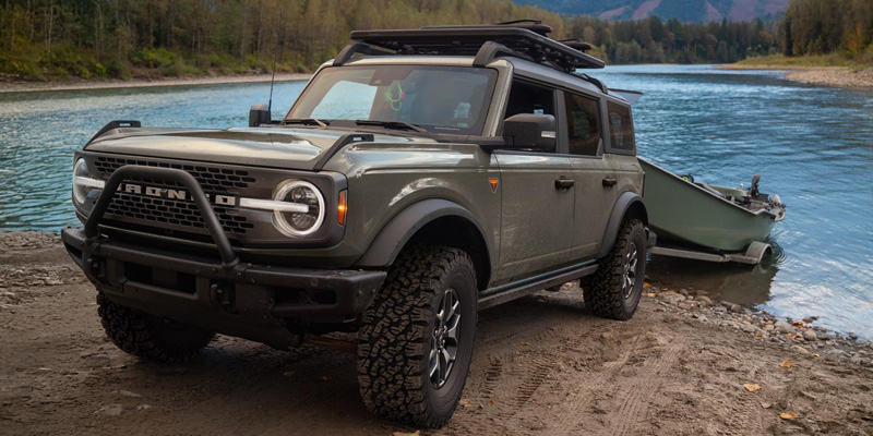 Ford Bronco parked beside a river, showcasing its rugged design and outdoor adventure capabilities.